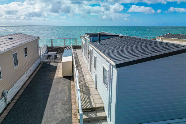 Coastal mobile homes by the sea with clear blue sky and ocean views, ideal vacation spot for relaxation.