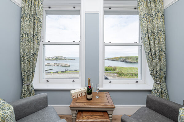 Stylish seaside view from a UK property captured by a North Wales photographer. Cozy interior, ocean, Moët bottle on table.