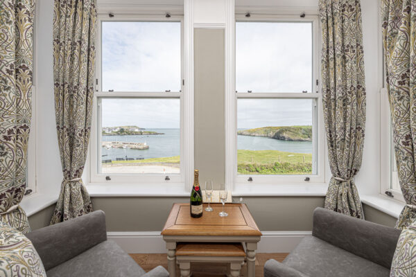 Cozy seating by window with coastal view, featuring champagne; captured by UK property photographer, North Wales.