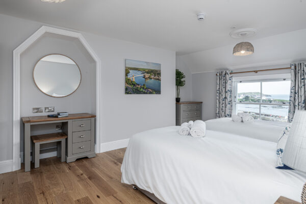 Elegant bedroom captured by UK property photographer, North Wales with coastal views, white linens, and decor.