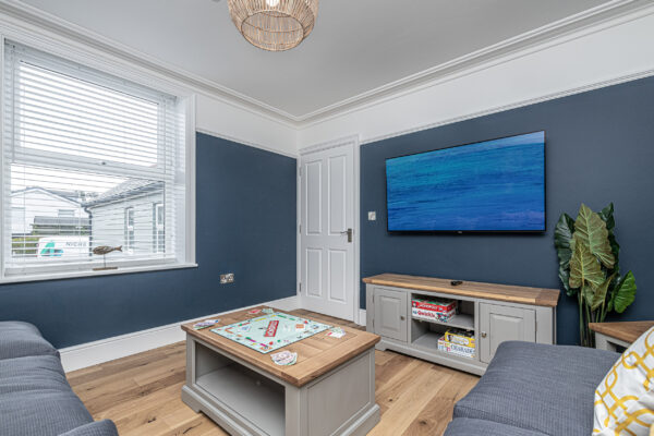Living room with blue walls, wood decor, by UK property photographer in North Wales. Cozy interior design.