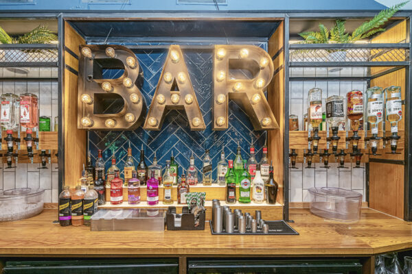 Stylish bar setup captured by a UK property photographer, showcasing vibrant bottles and a marquee sign in North Wales.