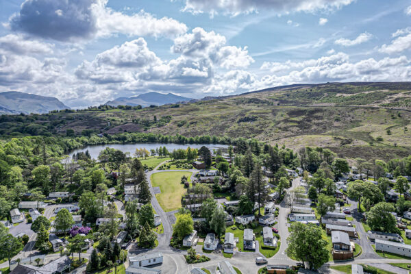 Aerial view of scenic North Wales landscape by UK property photographer, capturing lush hills and a serene lakeside village.