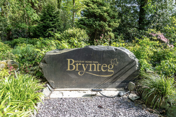 Brynteg Holiday Home Park sign amidst lush greenery, captured by UK property photographer in North Wales.