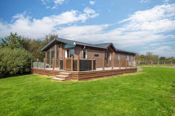 Modern UK property photo by North Wales photographer, showcasing a stylish wooden home with green lawn.